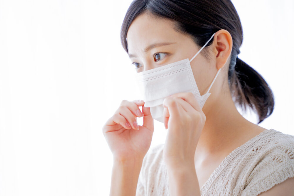 マイコプラズマ感染症の飛沫感染対策としてマスクをする女子学生のイメージ